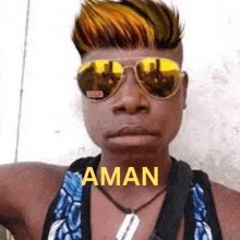 a man wearing sunglasses and a necklace with the word aman on his chest .