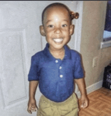 a young boy wearing a blue shirt and khaki shorts is smiling