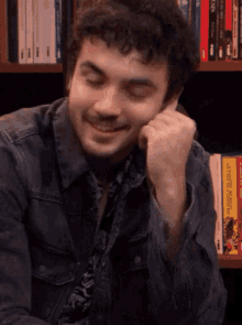 a man sitting in front of a bookshelf with a yellow book titled " the master of tricks " on it