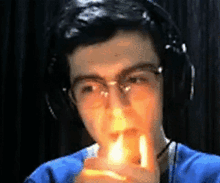 a man wearing glasses and headphones is lighting a candle