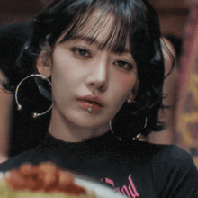 a woman wearing hoop earrings and a shirt that says end