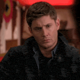 a man in a black jacket is looking at the camera with a serious look on his face