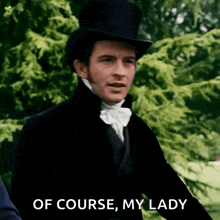 a man in a top hat and bow tie is standing in front of trees .