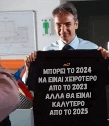 a man is holding a black shirt that says ' mtopei to 2024 ' on it