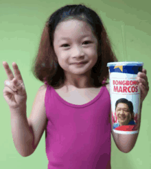 a little girl holding a bongbong marcos cup with a straw