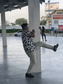 a man leaning against a pillar in front of a foodland superstore