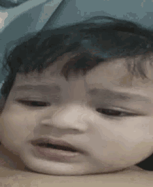 a baby is making a funny face while laying on a bed .