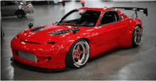 a red sports car is parked in a garage with a spoiler on the roof .