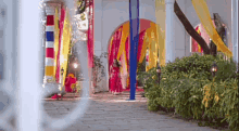 a woman in a red dress is walking down a sidewalk in front of a building decorated for a wedding .