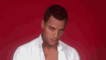 a man in a white shirt is looking at the camera against a red background