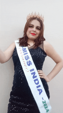 a woman in a black dress is wearing a miss india sash