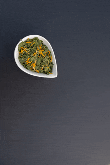 a white bowl filled with green and orange leaves