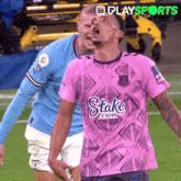 a soccer player wearing a pink shirt with stake.com on it