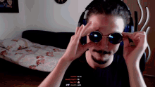 a man wearing sunglasses and headphones looks at the camera while someone says " headshot you no "