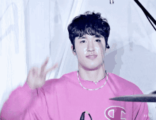 a man wearing a pink shirt with the letter c on the front