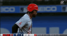 a baseball player wearing a red helmet stands in front of a scoreboard that says ' lyles pai ' on it