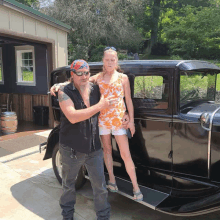 a man and a woman standing next to an old car