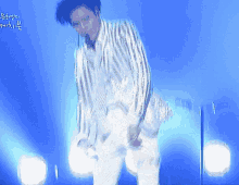 a man in a striped suit is dancing on a blue stage