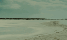 a person walking on a beach with a boat in the background