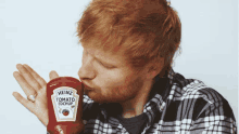 a man in a plaid shirt is kissing a heinz tomato ketchup bottle