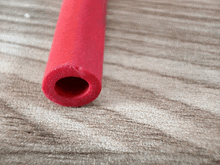 a red pipe with a hole in the middle is on a wooden surface