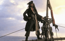 a man dressed as a pirate stands on a boat in the ocean