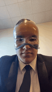 a man in a suit and tie has duct tape wrapped around his head