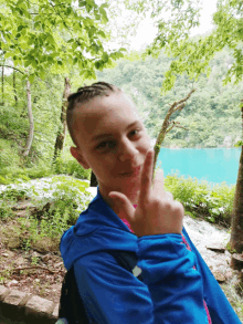 a young boy in a blue jacket giving a peace sign