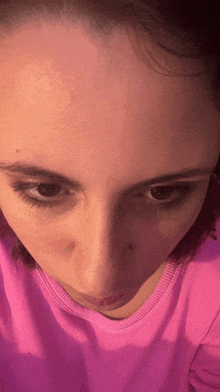 a close up of a woman 's face in a pink sweater