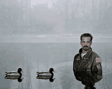 a man in a military uniform is standing in a lake surrounded by ducks .