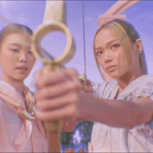 two women are holding a gold object in front of them