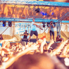 a man stands on a stage in front of a crowd with a sign that says ' ibiza beach ' on it