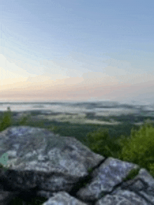 a group of rocks sitting on top of a mountain with a view of a valley .