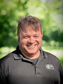 a man wearing a black polo shirt that says local roots landscapes