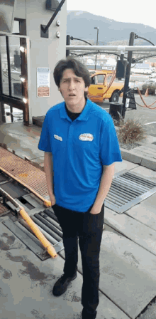 a man wearing a blue shirt that says ' car wash ' on it is standing in front of a car wash