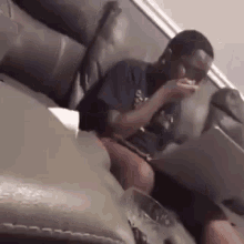 a man is sitting on a couch eating a piece of food .