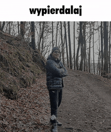 a man standing on a path in the woods with the words wypierdalaj below him