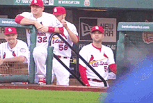 a group of baseball players are sitting in a dugout and one of them has the number 32 on his jersey