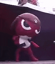 a red cartoon character is standing in front of a black background .