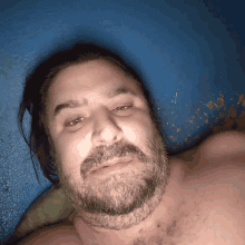 a man with a beard and long hair is laying on a blue surface