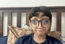 a boy wearing glasses is making a funny face while laying on a bed