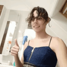 a woman is giving a thumbs up in a bathroom .