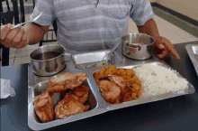 a man sitting at a table with a tray of food