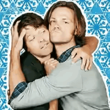 two men are hugging each other in front of a blue snowflake pattern .