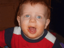 a young boy with his tongue hanging out is wearing a red and white shirt