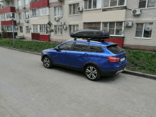 a blue car with a black roof rack is parked in front of a building