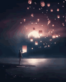 a girl is holding a lantern in the air while lanterns are flying in the night sky .