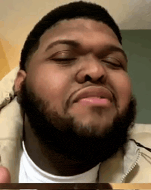 a man with a beard is making a funny face while looking at the camera .