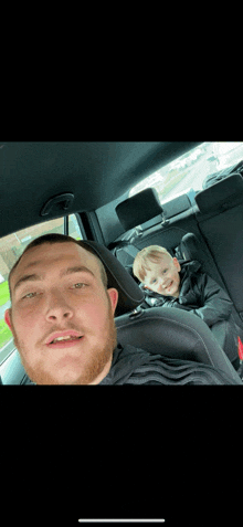 a man is sitting in the back seat of a car with a little boy in the back seat