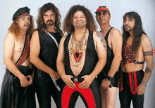 a group of men are posing for a picture and one of them is wearing a necklace with a heart on it